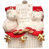 A white wicker gift basket for a twins first christmas with a white bear, plaque and a christmas outfit.
