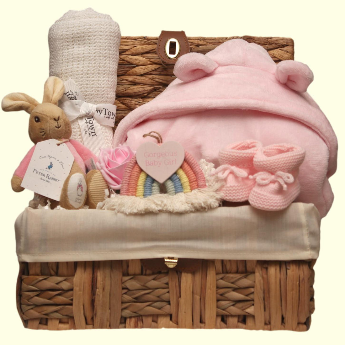 Flopsy Baby gift basket with white blanket, booties, and toys in a wicker basket.