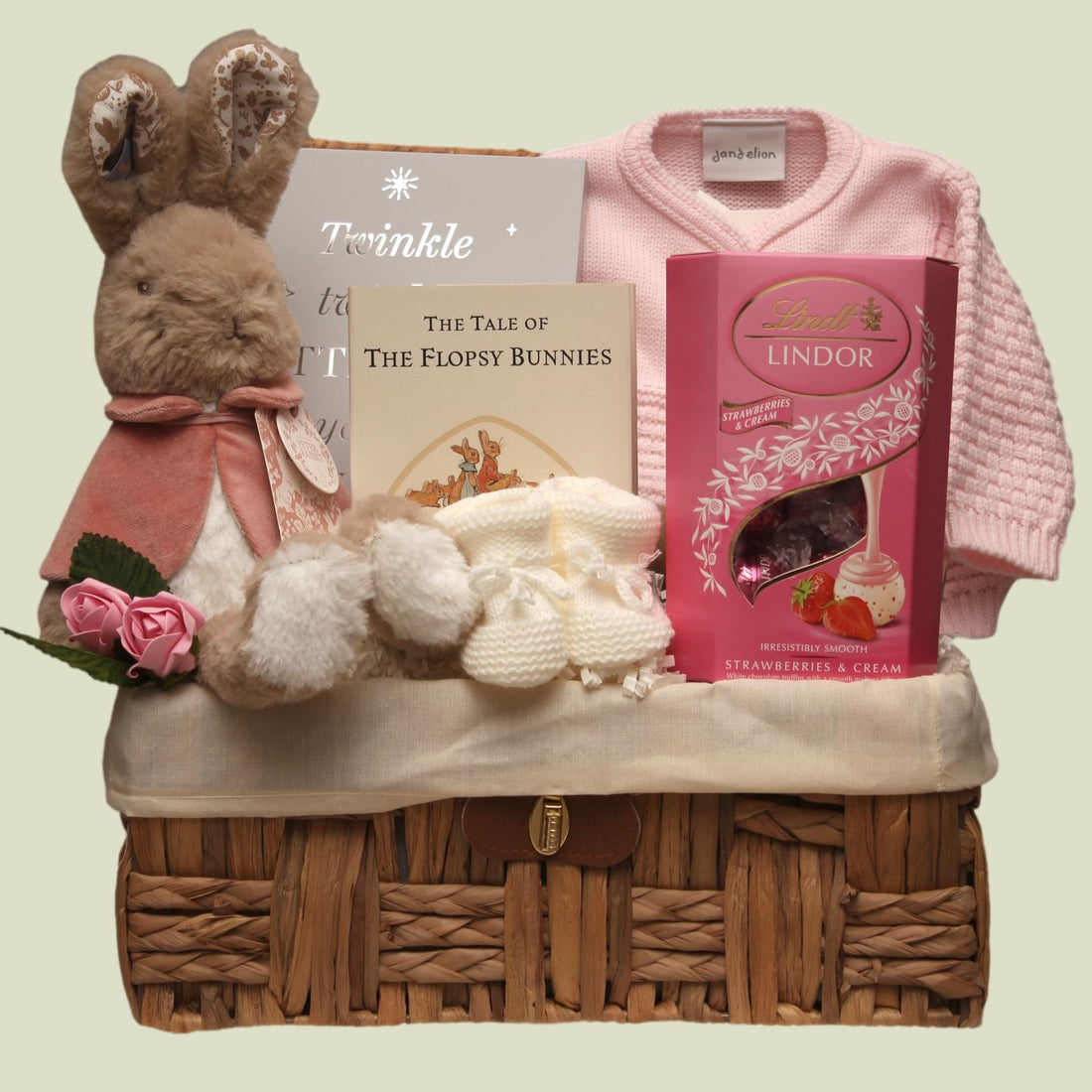 sea grass basket with Flopsy rabbit, book, Lindor chocolate, and a knitted cardigan and other baby keepsakes.