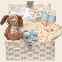 Baby gift basket with a little nutbrown hare, books, and milestone cards in a white basket.