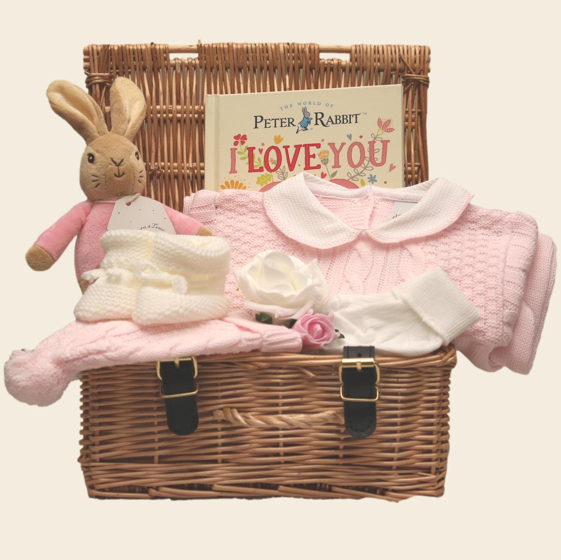 wicker hamper baby gift basket with flopsy bunny, knitted onesie, pink blanket, toy, and book