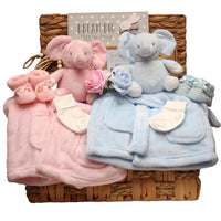 Baby twins gift set with plush elephant toys in blue and pink, matching dressing gowns and a 'Dream Big Little One' sign arranged in a basket. 
