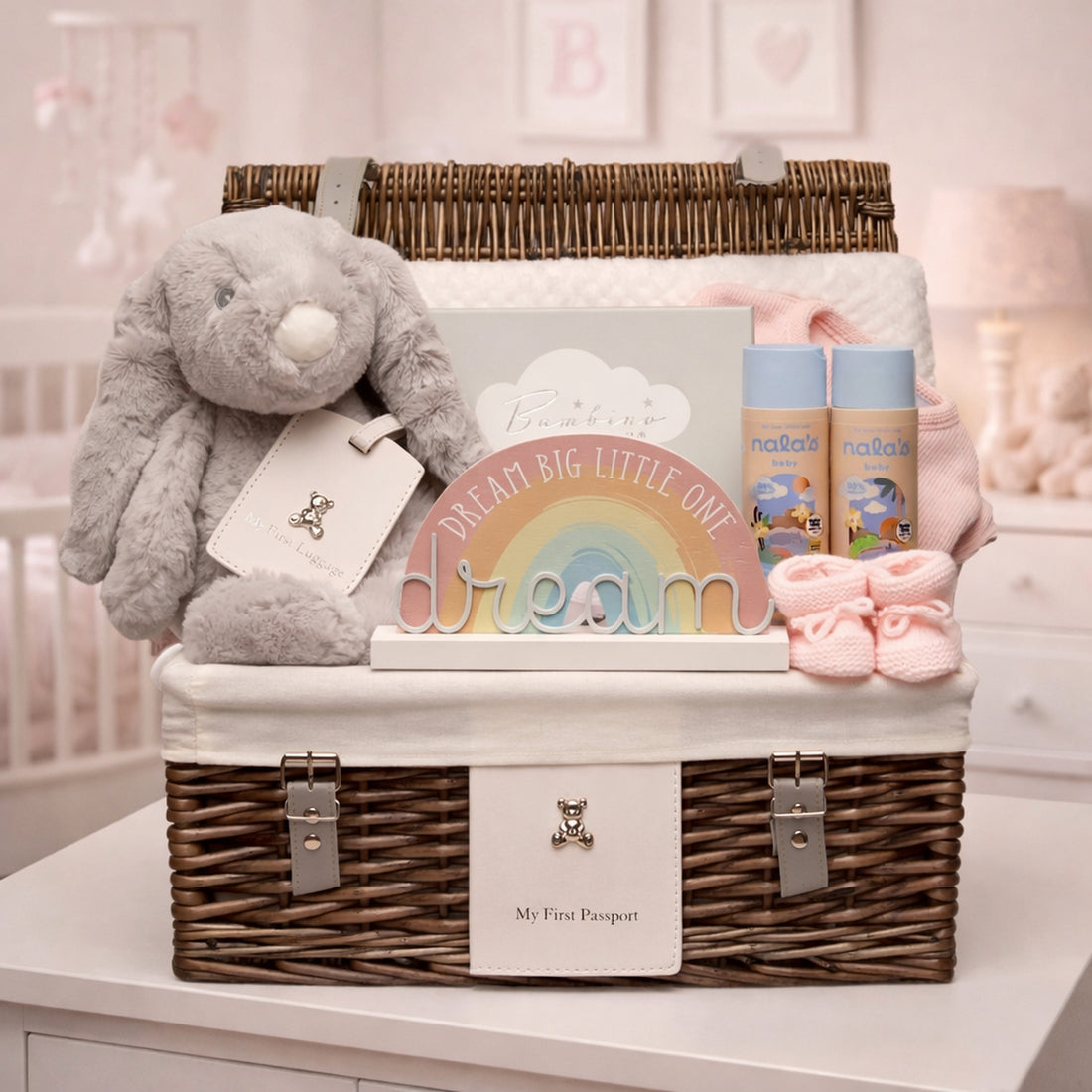 Luxury baby girl gift hamper in wicker basket displayed in pink nursery with bunny, keepsake gifts and baby essentials