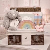 Luxury baby girl gift hamper in wicker basket displayed in pink nursery with bunny, keepsake gifts and baby essentials