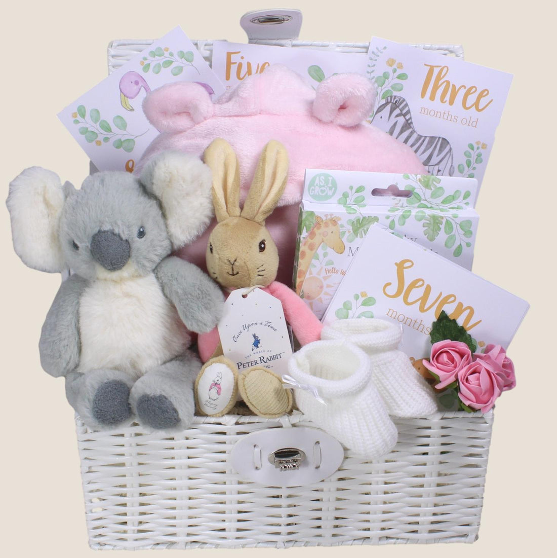 Baby gift basket with plush toys and milestone cards on a beige background