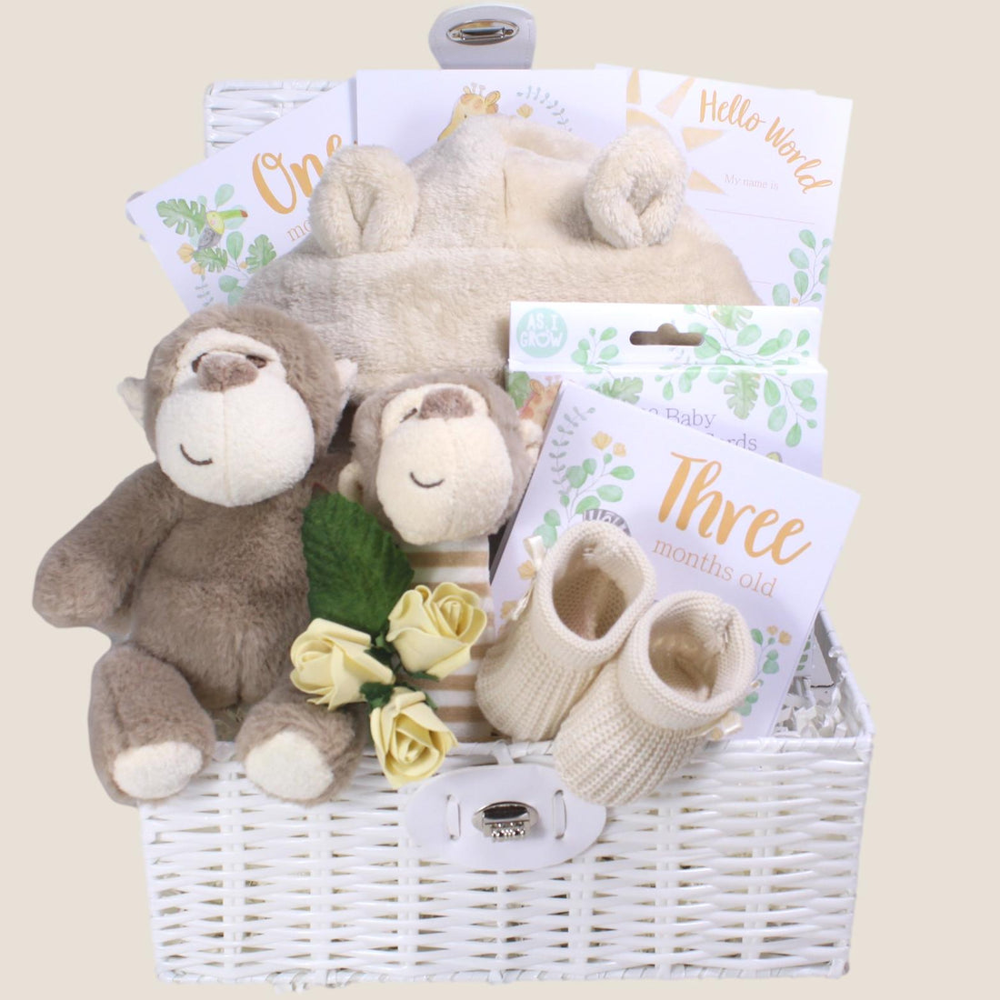 Baby gift basket with plush toys, shoes, and milestone cards on a beige background