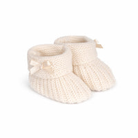 Pair of cream-colored knitted baby booties with ribbons on a white background